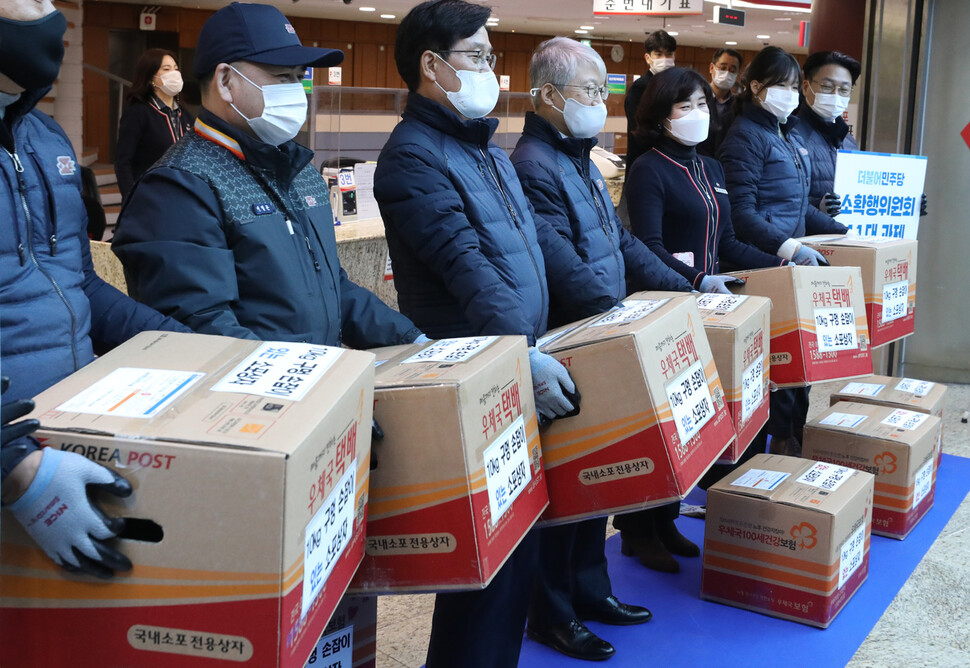 23일 서울중앙우체국에서 과학기술정보통신부 최기영 장관(오른쪽 넷째)과 민주당 신동근 의원(오른쪽 다섯째) 등이 구멍손잡이가 있는 소포상자를 들어보고 있다. 소포상자 구멍손잡이는 운반편의를 위해 만들었다. 공동취재사진