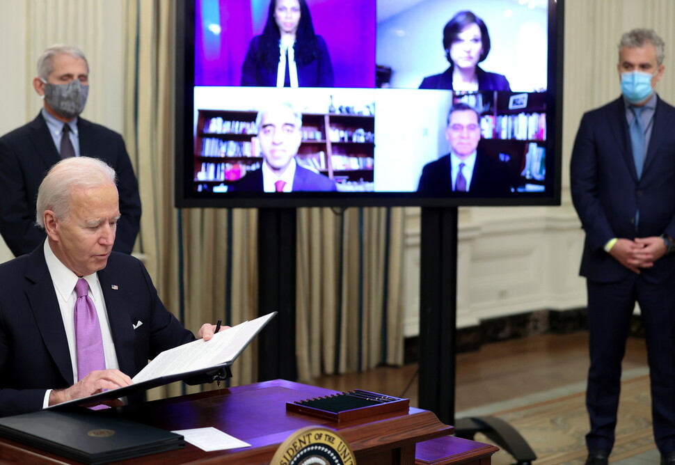 바이든 미국 대통령이 21일(현지시간) 백악관에서 앤서니 파우치 국립알레르기·전염병연구소 소장(왼쪽)이 지켜보는 가운데 코로나19 대응에 관한 행정명령에 서명하고 있다. ㈜연합뉴스