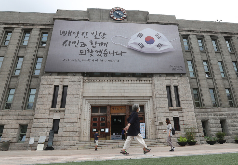 13일 오전 서울 중구 서울도서관 꿈새김판 `빼앗긴 일상, 시민과 함께 되찾겠습니다' 앞으로 마스크를 쓴 시민들이 지나가고 있다. 백소아 기자