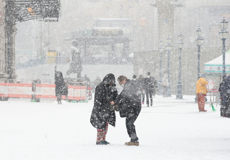 갑작스럽게 많은 눈이 내린 지난 18일 오전 서울 중구 서울역 앞에서 한 시민이 노숙인에게 자신의 방한점퍼와 장갑을 벗어 주고 있다. 백소아 기자 thanks@hani.co.kr
