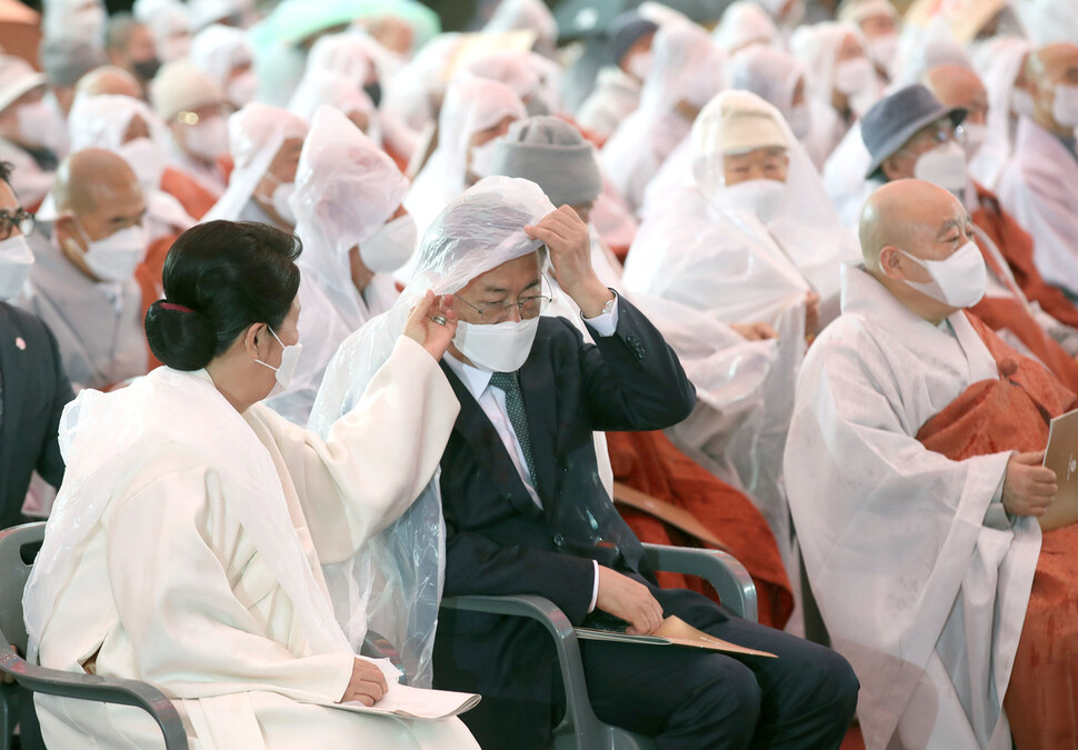 30일 서울 종로구 조계사에서 열린 조계종 제15대 종정 추대법회에서 갑작스러운 비가 내리자 김정숙 여사가 문재인 대통령의 비옷을 챙겨주고 있다. 청와대사진기자단