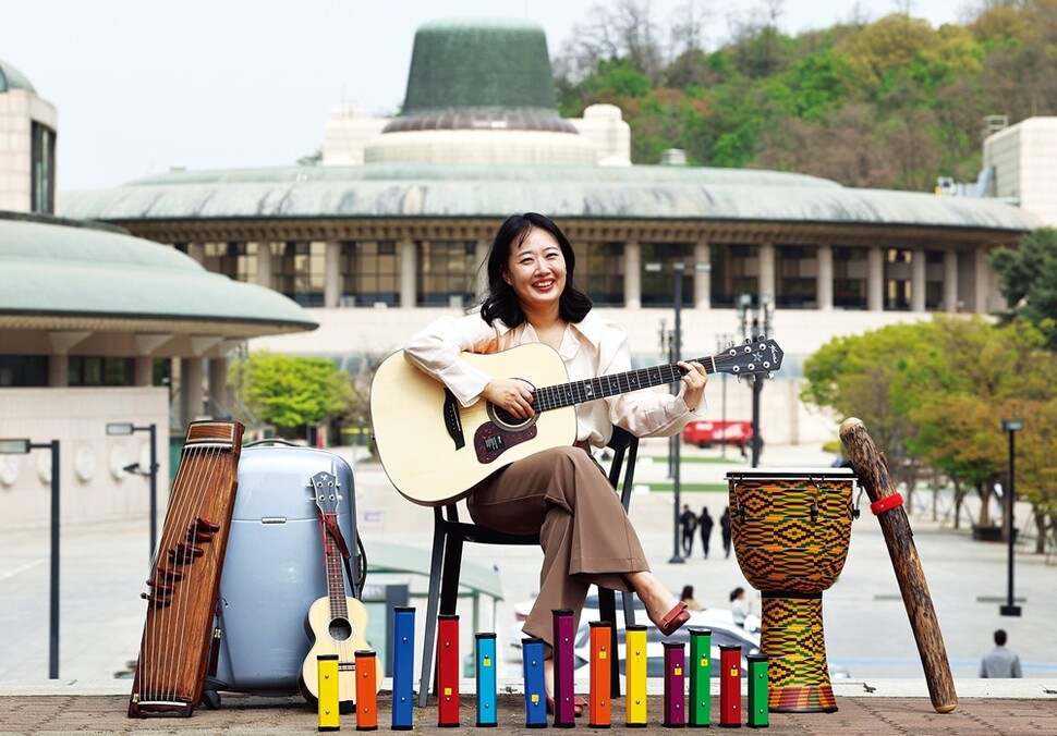 구수정 음악치료사가 지난 14일 서초구 예술의전당에서 음악치료에 주로 사용되는 노래를 기타로 연주하고 있다. 구수정 치료사 주변에 음악치료에 쓰이는 다양한 악기들이 전시돼 있다. 왼쪽부터 가야금, 우쿨렐레, 한 음씩 분리되는 실로폰, 젬베, 레인스틱(빗소리를 내는 악기).