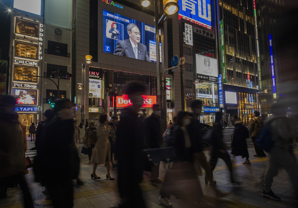 18일 오후 스가 요시히데 일본 총리가 수도권 긴급사태 해제 관련 기자회견에서 발언하고 있는 모습이 도쿄 신주쿠 빌딩에 걸린 대형 화면을 통해 보이고 있다. 도쿄/AP 연합뉴스