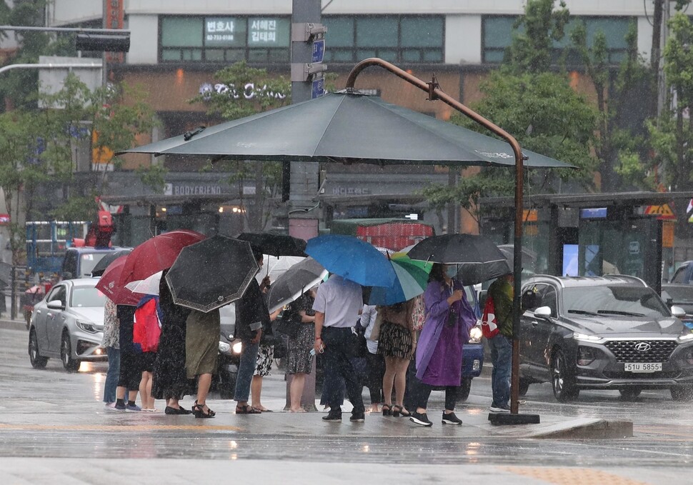 본격적인 여름 장마가 시작된 24일 오전 서울 종로구 광화문 네거리 일대에서 우산을 쓴 시민들이 햇빛가리개 아래에서 신호를 기다리고 있다. 백소아 기자