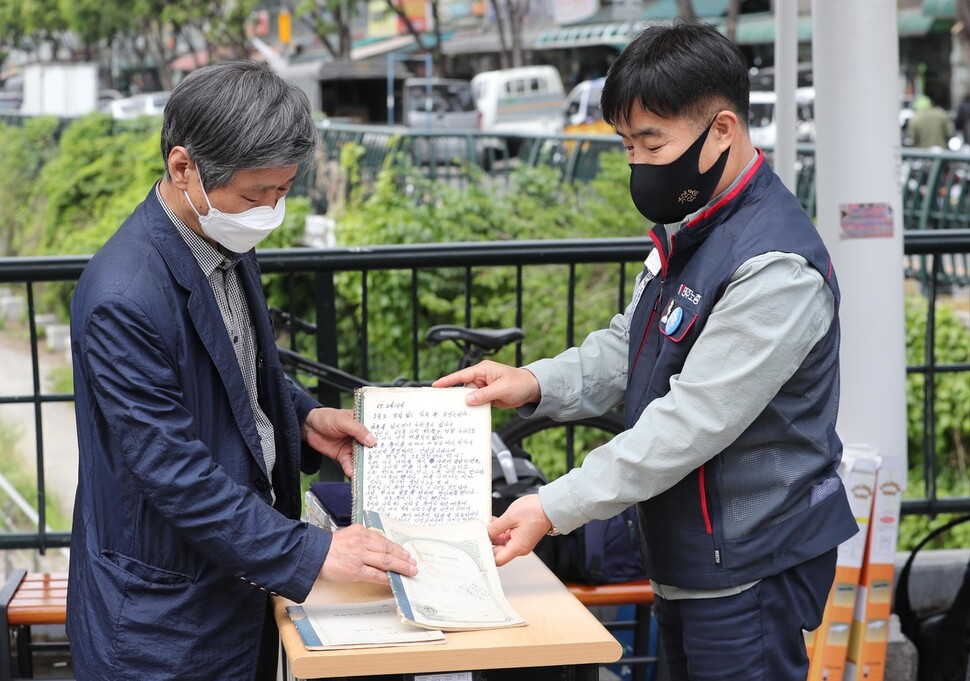 전태일 열사의 동생 전태삼(왼쪽)씨가 29일 서울 청계천 버들다리 전태일 동상 앞에서 일기장 원본 7권의 관리를 위임받은 ‘전태일 일기장 관리위원회’에 일기장을 위임하며 이를 공개하고 있다. 강창광 선임기자