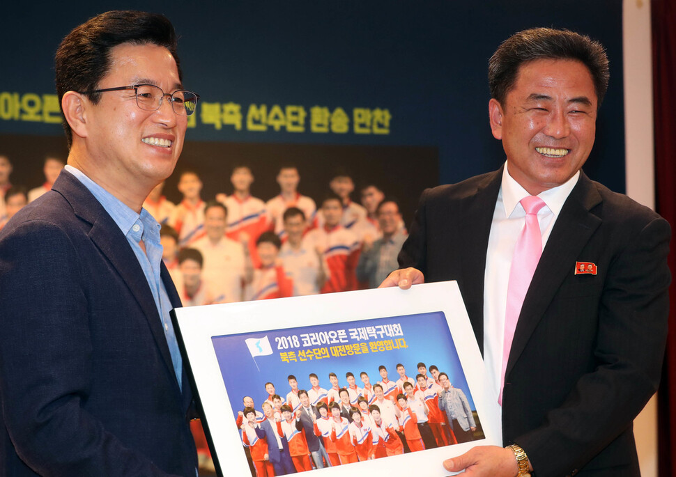 2018 코리아오픈 탁구대회에 북쪽 선수단을 이끌고 참가한 주정철 북한탁구협회 서기장(오른쪽)이 2018년 7월21일 오후 대전시청 20층에서 열린 환송만찬에서 허태정 대전시장한테서 사진 선물을 받고 있다. 연합뉴스