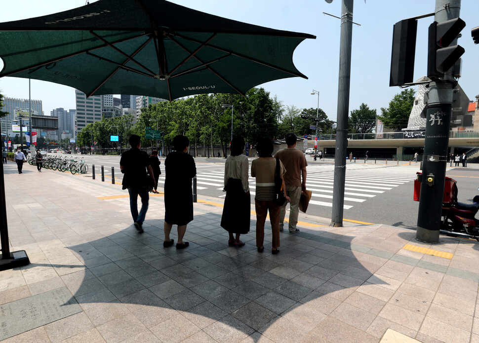 8일 오후 시민들이 서울 중구 그늘막이 설치된 건널목에서 잠시 더위를 피하고 있다. 이종근 기자