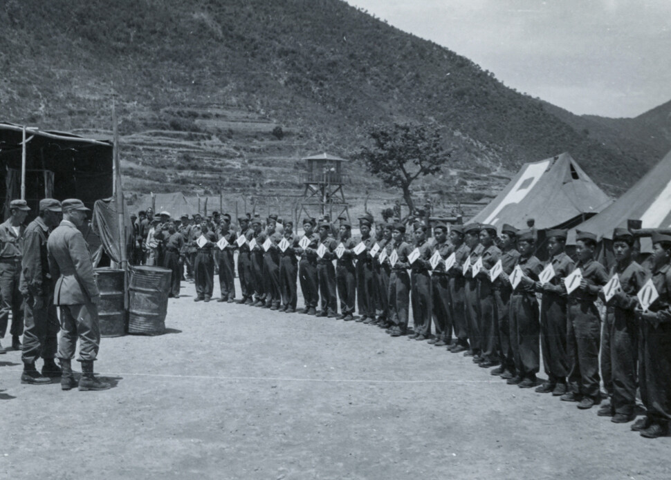 1951년 6월 5일 거제 포로수용소 7구역을 찾은 국제적십자위원회 프레데릭 비에리 대표단원을 향해 “거제 수용소는 지상낙원”이라는 손팻말 들고 환영하고 있다.&nbsp;