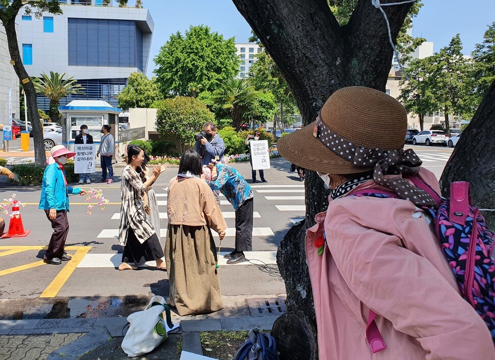 제성마을 양 할머니가 17일 제주시청 앞 구실잣밤나무 아래서 주민과 문화예술들이 함께하는 집회를 보고 있다.