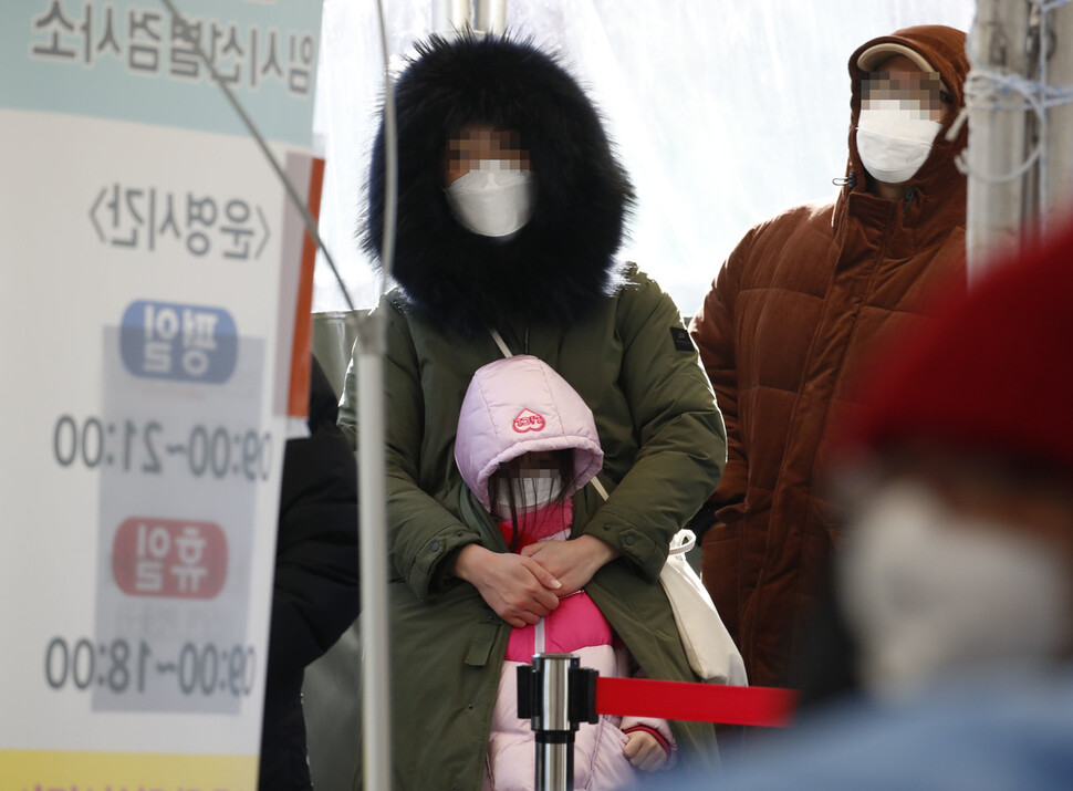 올해 들어 가장 추운 날씨를 보여 전국 대부분 지역에 한파특보가 발효된 26일 오전 서울 중구 코로나19 임시선별검사소에서 검사를 받으러 온 한 시민이 아이를 외투로 안아준 채 줄 서 순서를 기다리고 있다. 김혜윤 기자