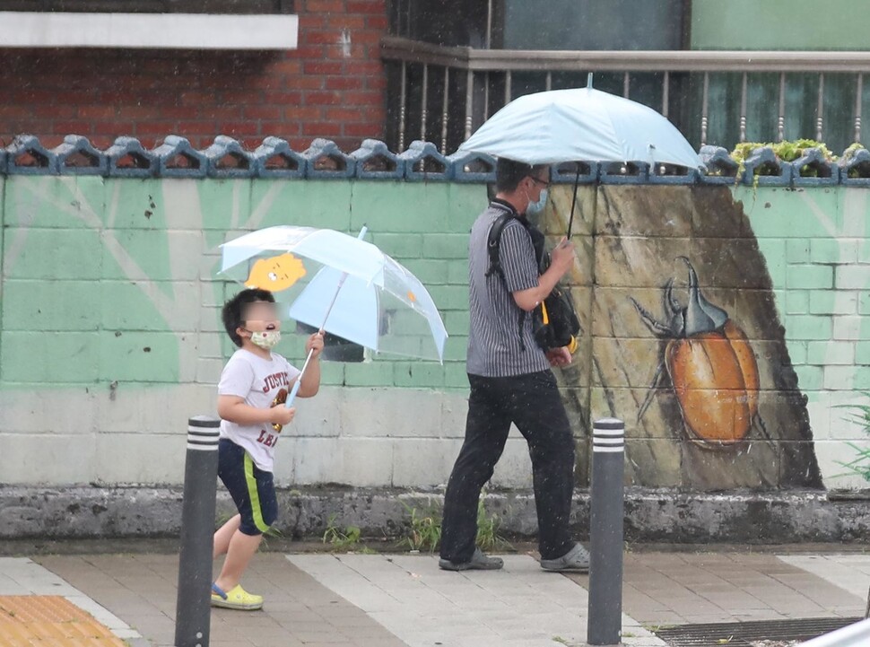 본격적인 여름 장마가 시작된 24일 오전 서울 마포구 만리재로에서 한 어린이가 우산을 가지고 장난을 치며 길을 건너고 있다. 백소아 기자