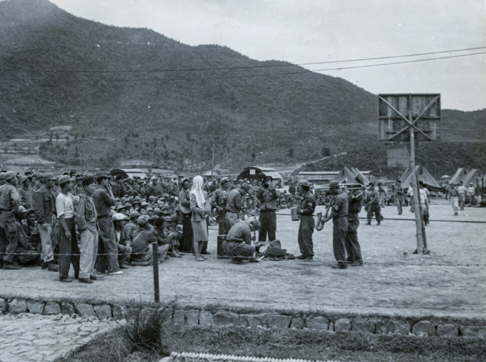 1951년 6월 거제 포로수용소에서 포로들이 나무와 깡통으로 만든 악기로 재즈 오케스트라를 모방한 공연을 하는 모습. 옆에는 국제적십자위원회 지원으로 만들어진 농구 골대가 설치돼 있다.&nbsp;