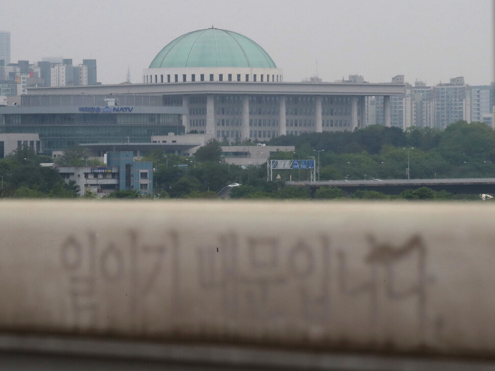 20대 국회 임기 종료를 24일 앞둔 5일 서울 마포대교 위에서 바라본 국회의 모습이 흐릿하게 보이고 있다. 마포대교 난간에 ‘일이기 때문입니다’라고 적혀 있다. 20대 국회에 계류된 법안은 1만5256건으로 마지막 본회의를 열지 못하면 모두 폐기될 예정이다. 백소아 기자 thanks@hani.co.kr