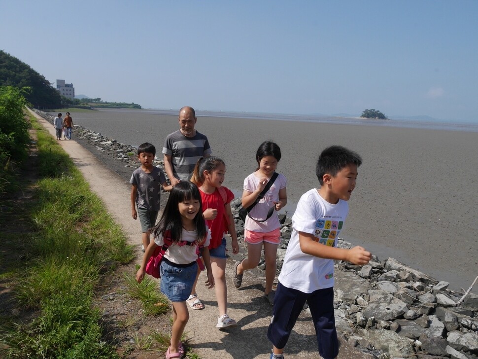 전남 순천사랑어린학교 김민해 교장선생님과 아이들이 해변을 따라 학교로 등교하고 있다.