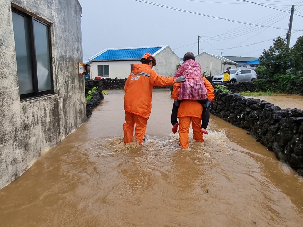 지난 4일 오후 제주 서귀포시 대정읍 영락리의 마을 안 길이 침수되자 소방대원이 주민을 업고 나오고 있다. 제주도 소방안전본부 제공