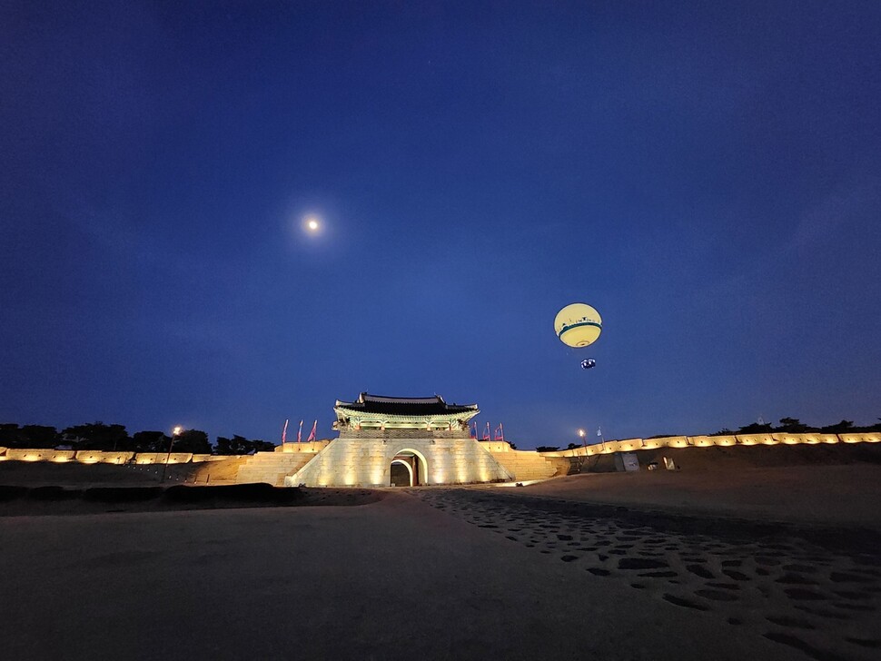 수원화성 동쪽에 있는 창룡문의 야경. 하늘에 달과 헬륨 기구인 ‘플라잉수원’이 떠 있다. 허윤희 기자