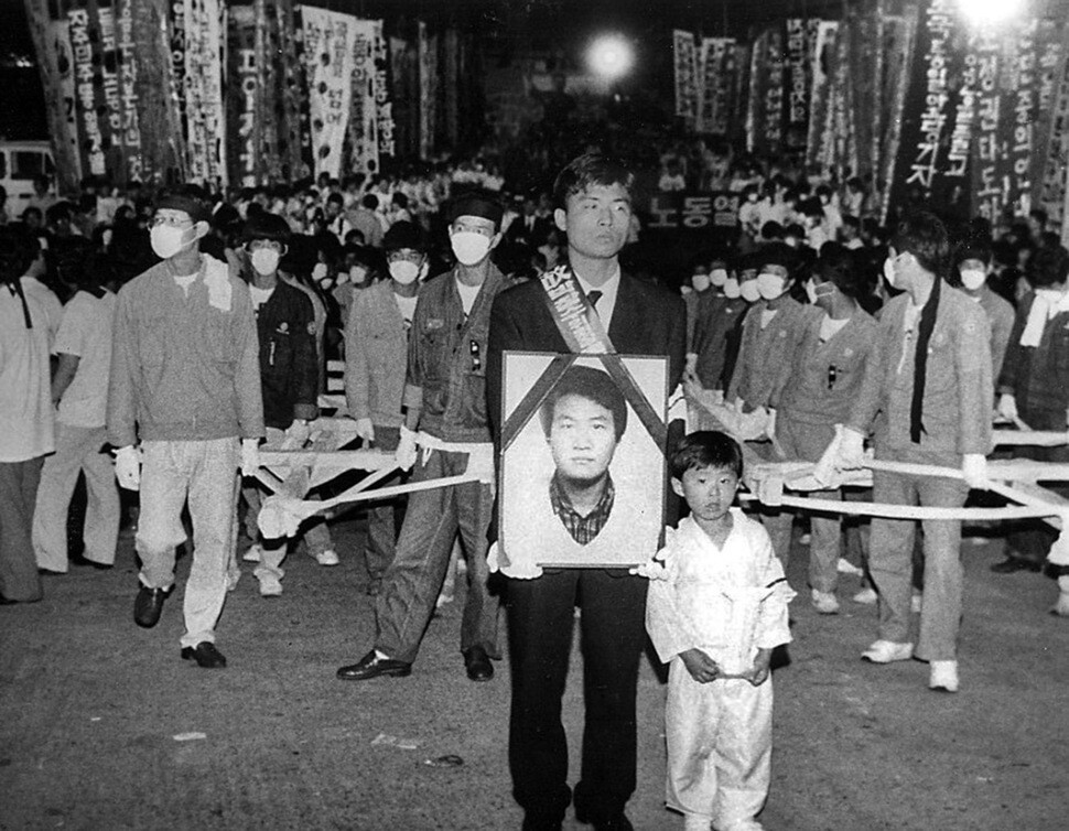 1991년 6월 30일 고 박창수씨의 아들 용찬군이 부산 한진중공업에서 영결식을 마치고 노제를 지내기 위해 회사 정문을 나서는 장례행렬의 선두에 서서 행진하고 있다.&lt;한겨레&gt; 자료사진