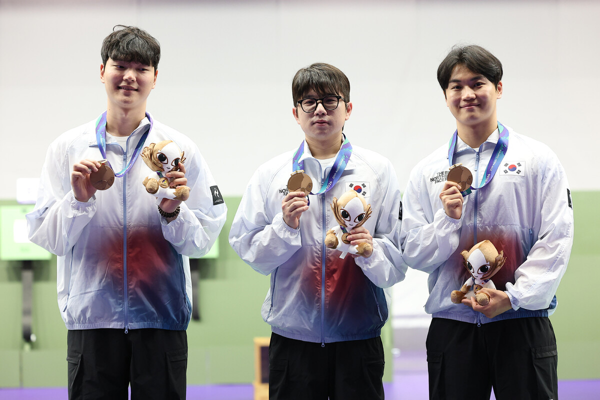 신민기(왼쪽), 박하준(가운데), 권협준이 21일 일본 아이치현 종합 사격장에서 열린 2026 아이치·나고야 아시안게임 사격 남자 10m 공기소총 단체전 시상식에서 메달을 들어 보이고 있다. 도요타/연합뉴스
