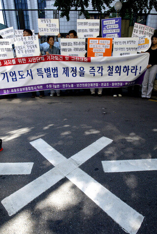 » 기업도시법은 민간 시행자가 사업 목적에 맞춰 도시 하나를 독자적으로 건설할 수 있도록 2004년에 제정됐다. 이 법에 따라 기업은 개발구역 토지의 2분의 1 이상을 확보하면 나머지 토지를 자동적으로 강제 수용할 수 있게 됐다. 2004년 9월22일 서울 세종로 정부중앙청사 앞에서 시민단체 회원들이 기업도시법 제정 철회를 요구하며 집회를 하고 있다. 한겨레 이정아 