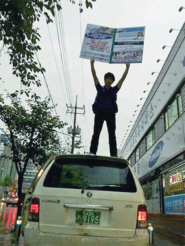 고 최종범씨가 자신의 낡은 자동차 위에 올라 삼성의 부당노동행위에 항의하는 1인시위를 벌이고 있다.삼성전자서비스지회 제공