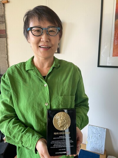 Yuka Okamoto, the joint director of the Tokyo committee to put on the “Non-Freedom of Expression” exhibit holds her 8th Seong Yu-bo Special Award at her home in Tokyo, Japan, on Dec. 28. (Kim So-youn/The Hankyoreh)