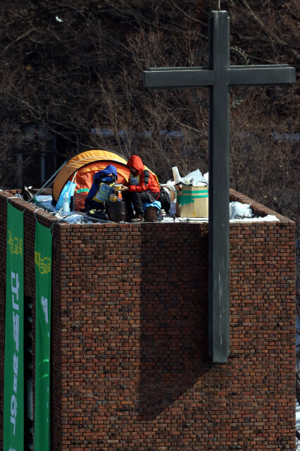 원직 복직과 단체협약 체결을 촉구하며 6일째 고공농성을 벌이고 있는 재능교육 해고노동자 오수영(오른쪽) 여민희 씨가 11일 낮 재능교육 본사를 마주보고 있는 서울 종로구 혜화동 성당 종탑에서 점심식사를 하기 위해 누룽지가 든 1회용기에 더운물을 붓고 있다. 이정아 기자 leej@hani.co.kr