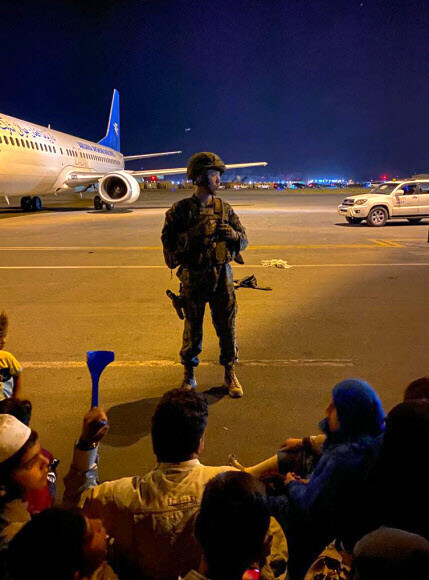 A US army soldier stands guard as Afghans wait to flee the country through Kabul’s international airport on Monday. (AFP/Yonhap News)