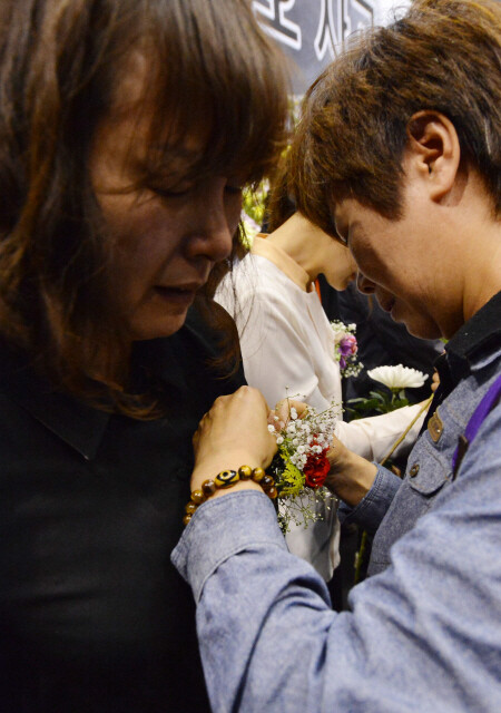  a family member of a student who perished in the Sewol ferry sinking weeps while pinning a carnation to the chest of a family member of a teacher who died