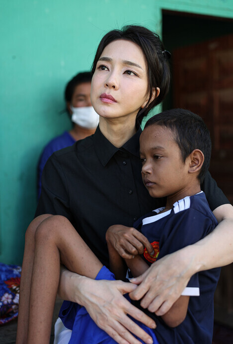 First lady Kim Keon-hee holds a Cambodian boy with a congenital heart condition at his home during her visit to the Southeast Asian nation on Nov. 12. (courtesy of the presidential office)