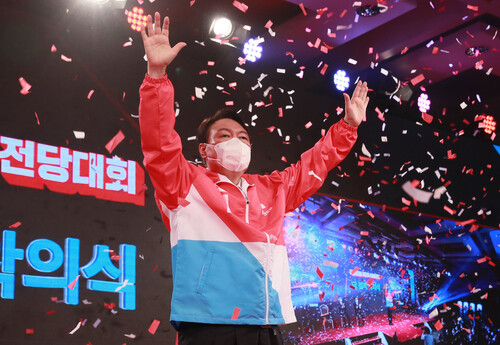 Dressed in a party jacket, People Power Party presidential nominee Yoon Seok-youl holds up his hands after being declared the winner of the main opposition party's presidential primary at the party's national convention held on Friday in Seoul. (National Assembly pool photo)