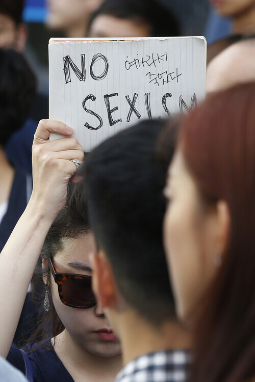An attendee of a memorial rally following the May 2016 Gangnam Station murder holds up a sign reading, “No sexism” and “She died because she was a woman.” (Lee Jeong-a/The Hankyoreh)