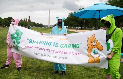 Protesters hold a sign reading “sharing is caring” to call for waiving patents of COVID-19 vaccines in front of the National Mall in Washington on Wednesday. (AFP/Yonhap News)