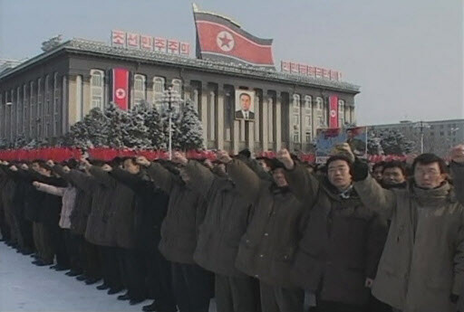  people are punching their fists into the air during a rally held at Kim Il Sung Square in Pyongyang