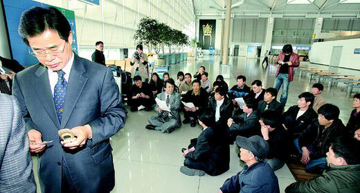  an official tries to call somewhere as the victims and their families sit-in at Incheon Airport
