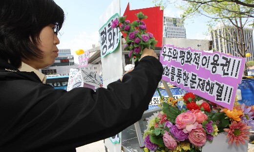  place flowers and hold up placards in front of the U.S. Embassy in Seoul