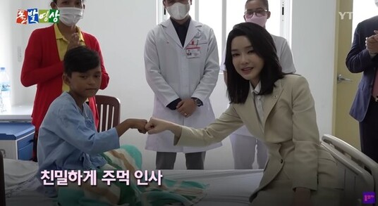 Still from a YTN program showing the first lady fist-bumping a boy in a hospital.