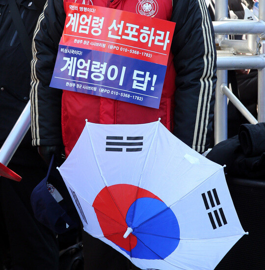A participant in a right wing rally in central Seoul on Feb. 11 holds a placard calling for the declaration of martial law. (by Kim Tae-hyeong