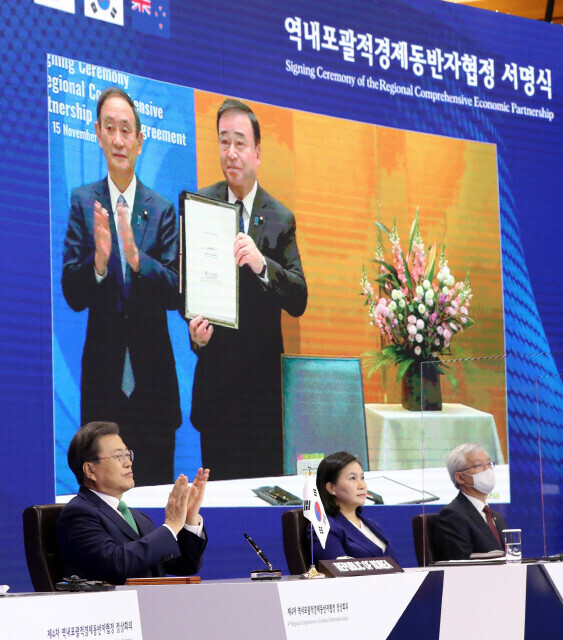 South Korean President Moon Jae-in applauds after Japanese Prime Minister Yoshihide Suga and Trade Minister Hiroshi Kajiyama (seen in the background) sign the Regional Comprehensive Economic Partnership (RCEP) agreement during the signing ceremony held via teleconference on Nov. 15, 2020. (provided by the Blue House)