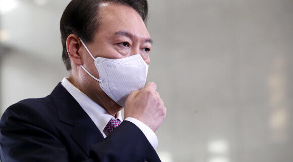 President Yoon Suk-yeol adjusts his mask while responding to questions from the press during his commute on Nov. 10. (Yonhap)