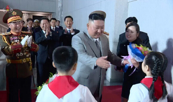 Kim passes along a flower bouquet received by North Korean children to popular singer and WPK Central Committee member Hyon Song-wol during a military parade celebration of the 75th anniversary of the WPK on Oct. 10. (KCTV screenshot/Yonhap News)