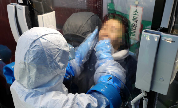 A health worker takes a sample in a single-person screening booth in front of H Plus Yangji Hospital in Seoul on Mar. 16. (Yonhap News)
