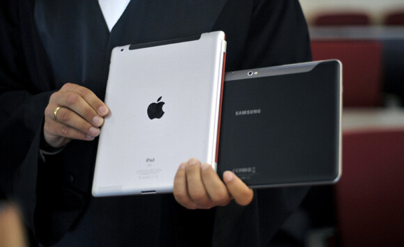  2011 file photo a lawyer holds an Apple iPad and a Samsung Tablet-PC at a court in Duesseldorf