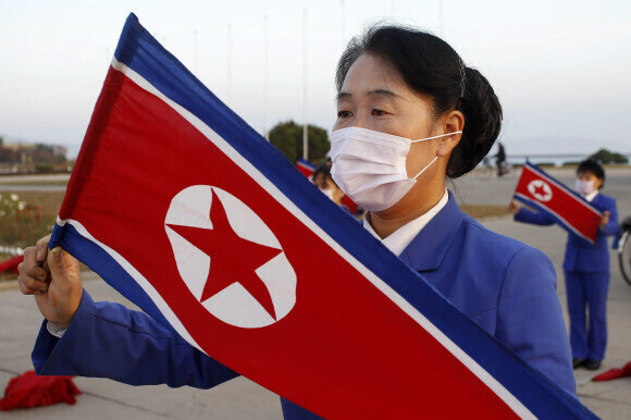 North Koreans wearing masks partake in a patriotic ceremony with North Korean flags in Wonsan, Kangwon Province, on Oct. 28. (Yonhap News)