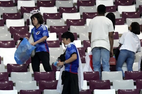 日本球迷在观看了他们的国家足球队在 2022 年卡塔尔世界杯上取得历史性胜利后清理体育场。 韩联社