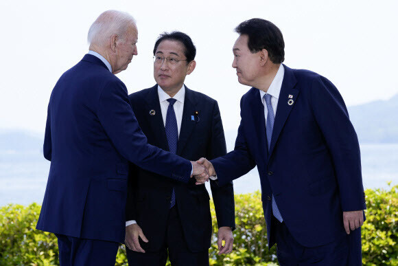 President Yoon Suk-yeol of South Korea (right) shakes hands with President Joe Biden of the US as they speak with Prime Minister Fumio Kishida of Japan on May 21 on the sidelines of the Group of Seven summit held in Hiroshima, Japan. (Yonhap)