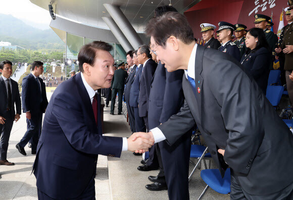 President Yoon Suk-yeol shakes hands with Democratic Party leader Lee Jae-myung while attending an Oct. 1 ceremony at the main parade ground at Gyeryongdae, South Chungcheong Province, to commemorate the 74th Armed Forces Day holiday. (Yonhap)