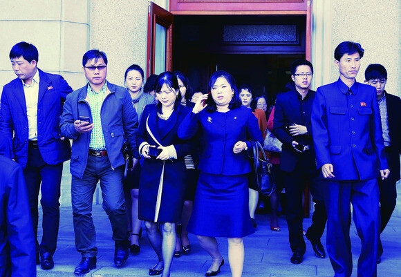 North Koreans with mobile phones in hand exit Pyongyang Grand Theatre after attending the April Spring Friendship Art Festival