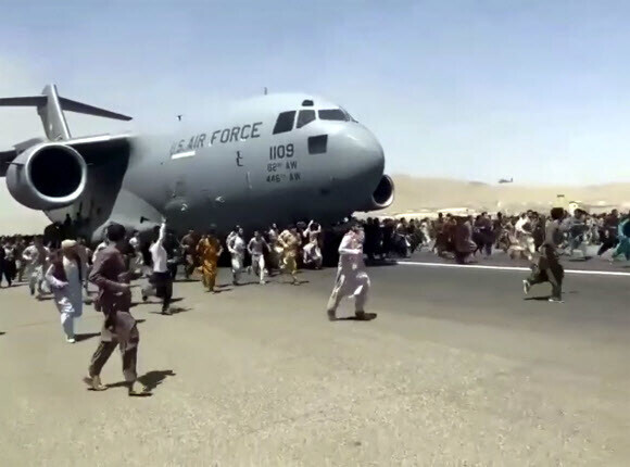 Hundreds of people run alongside a US Air Force C-17 transport plane as it moves down a runway of the international airport in Kabul, Afghanistan, on Monday. (AP/Yonhap News)