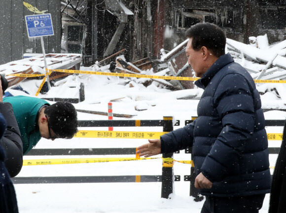 Han Dong-hoon, the interim leader of the ruling People Power Party, doubles over in a bow to President Yoon Suk-yeol while the two meet at the site of a major fire in South Chungcheong Province on Jan. 23. (Yonhap)