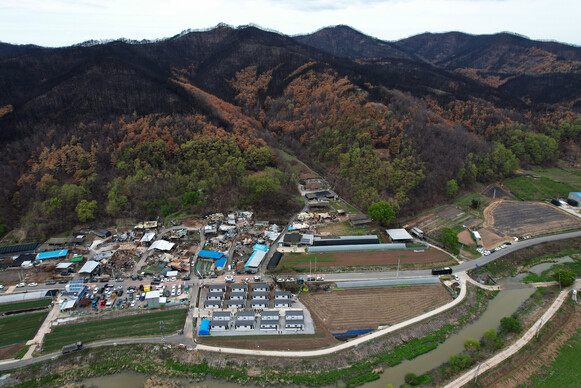 2025년 4월23일 오후 경북 안동시 일직면 명진리에서 산불로 집을 잃은 주민을 위한 이동주택(아래쪽) 입주식이 열리고 있다. 산 아래쪽에 불탄 집들이 보인다. 무인기를 띄워 찍었다.